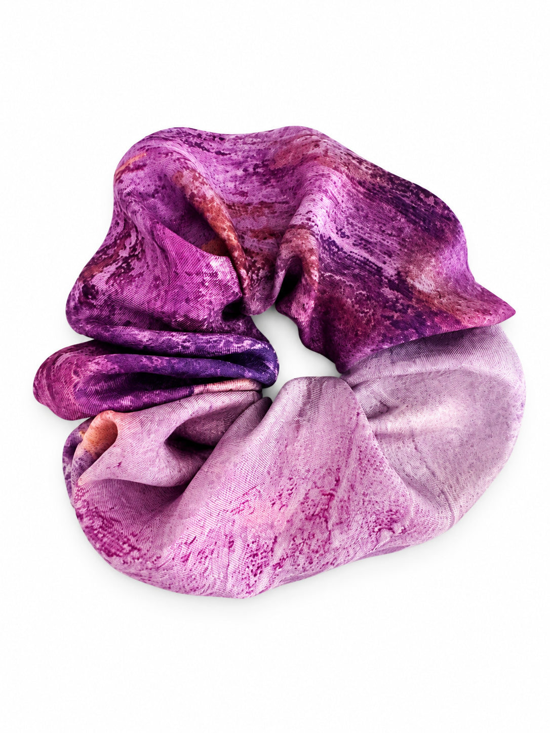 A fabric scrunchie with a marbled purple and pink pattern, shown on a solid white background.