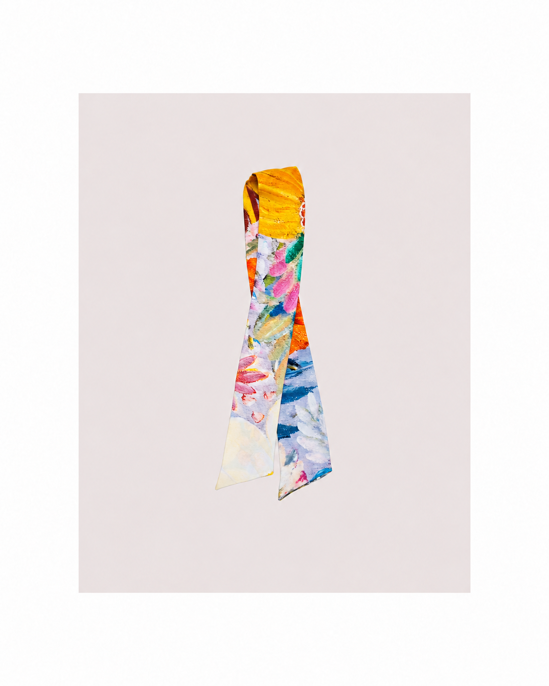 A folded silk scarf with a vibrant multicolor floral and abstract print, displayed against a solid pale pink background.